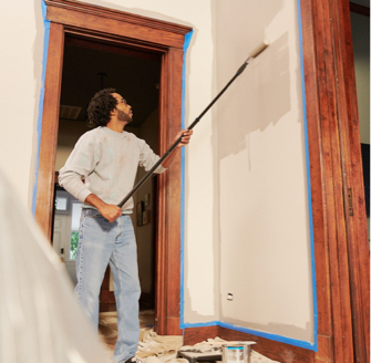 Professional painter painting an interior wall using a beige color.
